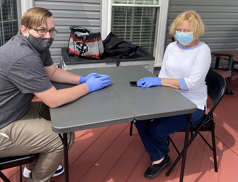 Cody and Wendy socially distancing at a folding table and chairs set up on Wendy's deck